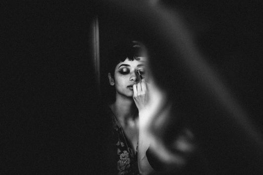 Black and white image of a busy woman applying Mistura Beauty's 6-in-1 Beauty Solution cosmetics.